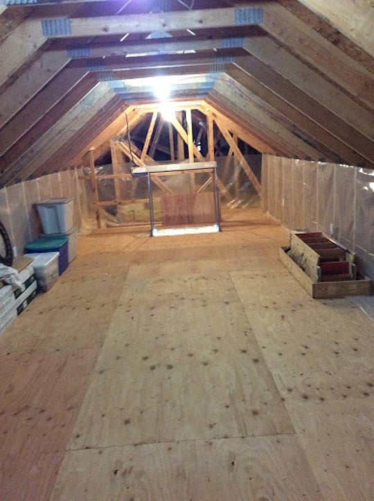 Interior of a clean attic with an attic lift in the distance