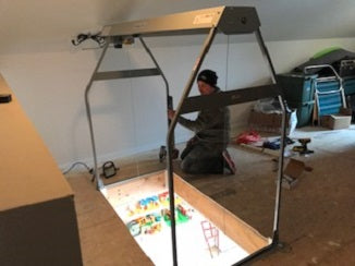 Person setting up a large light box in a room with various items scattered around.